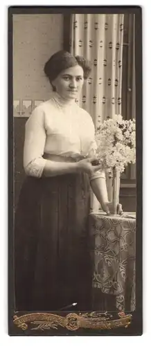 Fotografie Atelier Güttges, Zittau i. S., Frau steht am Tisch mit Blumenstrauss in Vase