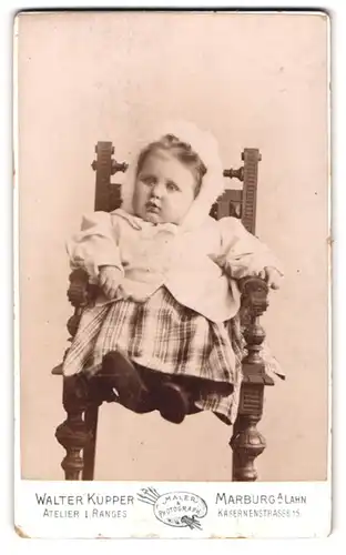 Fotografie Walter Küpper, Marburg a. Lahn, Kasernenstrasse 15, Kleinkind mit Haube auf Stuhl
