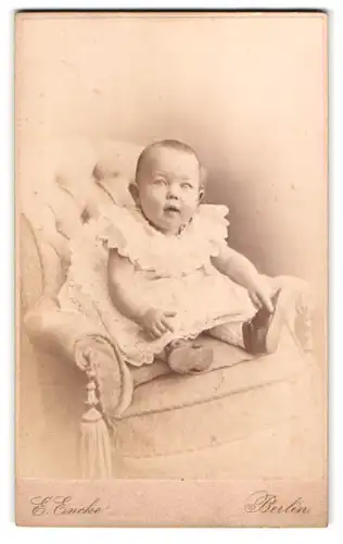 Fotografie E. Encke, Berlin, Potsdamer-Str. 125, Portrait Baby in weissem Kleid am Fauteuil