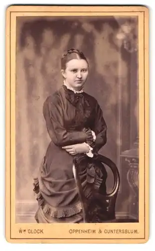 Fotografie W. M. Glock, Oppenheim, Am Dienheimer Tor, Junge Frau in schwarzem Kleid an Stuhl gelehnt