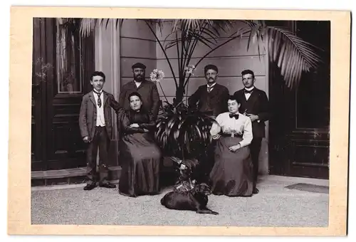 Fotografie unbekannter Fotograf und Ort, Familienportrait mit Hund unter grosser Palme, Kleinwüchsiger junger Mann