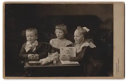 Fotografie H. Widensohler, Stuttgart, Königsstr. 21, Drei kleine elegante Kinder spielen an einem Tisch