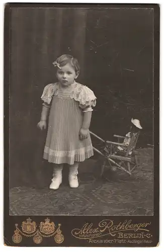 Fotografie Alex Rothberger, Berlin, Alexander-Platz, Portrait niedliches Mädchen im Kleid mit Puppe und Puppenkarren