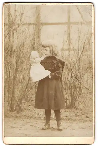 Fotografie unbekannter Fotograf und Ort, Portrait niedliches blondes Mädchen mit ihrer Handpuppe im Garten
