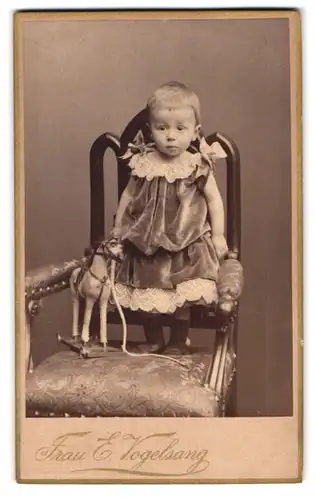 Fotografie Frau E. Vogelsang, Berlin, Leipzigerstr. 106, Portrait niedliches Mädchen im Samtkleid mit Spielzeugpferd