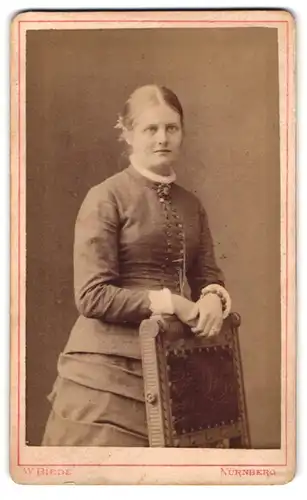 Fotografie W. Biede, Nürnberg, Lauferthorgraben 21, Junge Frau in elegantem Kleid an Stuhl gelehnt