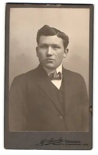 Fotografie H. Jacoby, Uelzen, Bahnhof- u. Achterstrassen-Ecke, Eleganter junger Mann im Anzug mit Fliege