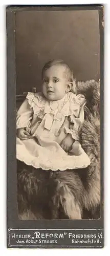 Fotografie Adolf Strauss, Friedberg i /H., Bahnhofstr. 9, Süsses Kleinkind im Kleid sitzt auf Fell
