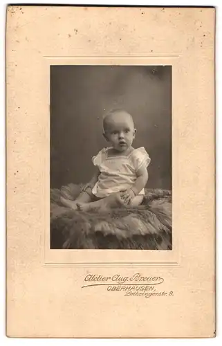 Fotografie Aug. Breuer, Oberhausen, Lothringerstr. 9, Süsses Kleinkind im Hemd sitzt auf Fell
