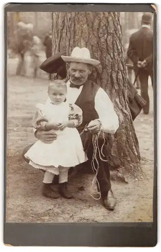 Fotografie unbekannter Fotograf und Ort, Grossvater mit seiner Enkeltochter lehnt an einer Kiefer