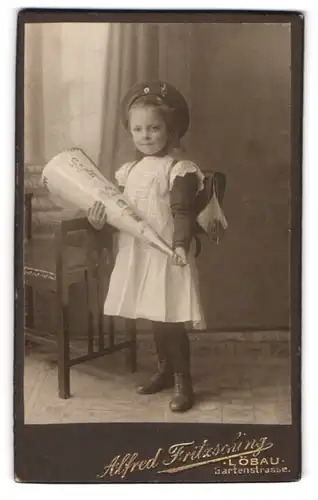 Fotografie Alfred Fritzsching, Löbau, Gartenstrasse, Mädchen im weissen Kleidchen mit Schultüte und Ranzen