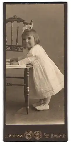 Fotografie J. Fuchs, Berlin, Hauptstr. 19, Portrait kleines niedliches Mädchen im weissen Kleid mit Haarschleife