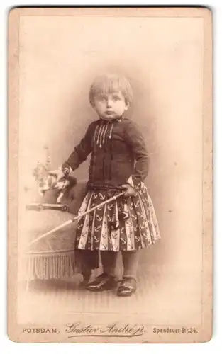 Fotografie Gustav Andre jr., Potsdam, Spandauer-Str. 34, Portrait Knabe Heinrich Haeberlin im Kleid mit Spielzeug Pferd