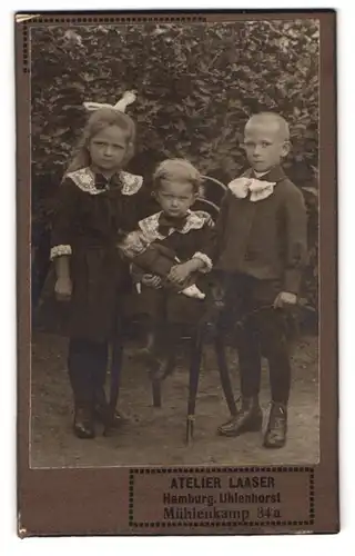 Fotografie Atelier Laaser, Hamburg, Mühlenkamp 34a, Portrait drei Kinder in Kleidern und Anzug mit Puppe