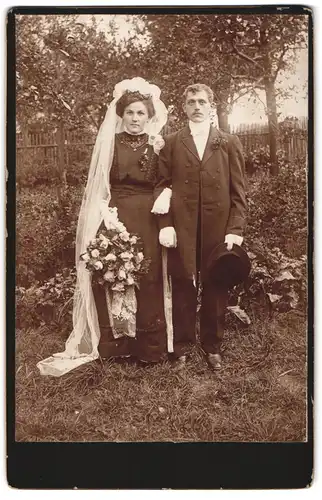 Fotografie unbekannter Fotograf und Ort, Portrait Brautpaar im schwarzen Kleid und Anzug mit Zylinder