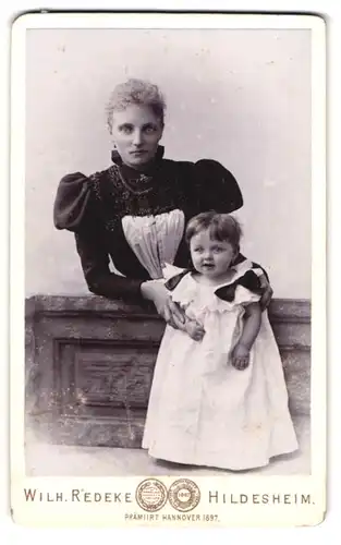 Fotografie Wilh. Redeke, Hildesheim, Kreuzstr. 22, Portrait Mutter im Biedermeierkleid mit ihre Tochter, Mutterglück
