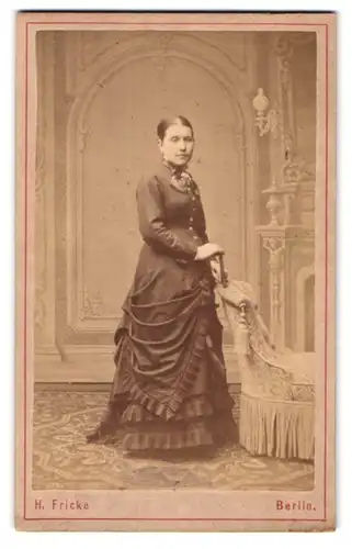 Fotografie H. Fricke, Berlin, Friedrichstr. 247, Portrait junge Frau im Biedermeierkleid am Sessel stützend