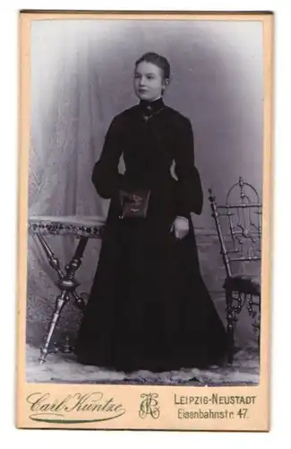 Fotografie Carl Kuntze, Leipzig, Eisenbahnstr. 47, Portrait Mädchen im schwarzen Kleid mit Bibel in der Hand, Kommunion