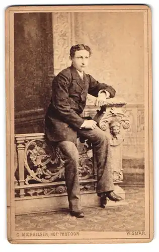 Fotografie C. Michaelsen, Wismar, Bürgerlicher junger Mann auf Ballustrade sitzend