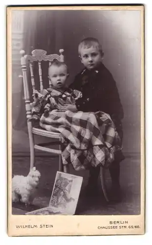 Fotografie Wilhelm Stein, Berlin, Chaussee Strasse 65 /66, Junge hält Kleinkind auf Stuhl fest