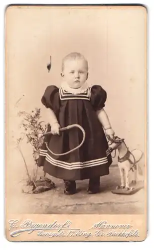 Fotografie C. Pagendorf, Hannover, Georgstr. 17 Eingang Gr. Packhofstr., Kleines Kind im Kleid mit Spielzeugpferd