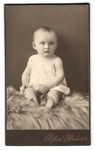 Fotografie A. Stöwer, Berlin-Schöneberg, Sedanstr. 1, Süsses Kleinkind im Hemd sitzt auf Fell