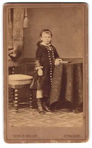 Fotografie Theodor Möller, Stralsund, Franken-Str. 5, Mädchen im Samtkleid lehnt am Tisch