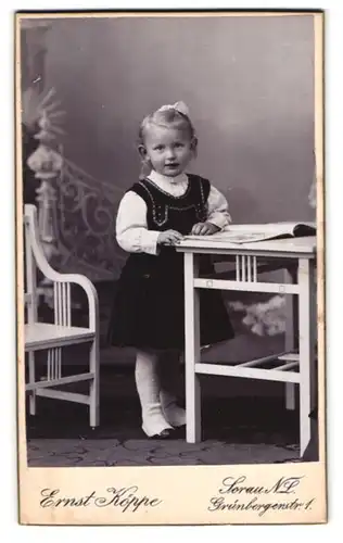 Fotografie Ernst Köppe, Sorau /N.-L., Grünbergerstr. 1, Kleines Mädchen im Kleid mit einem Heft