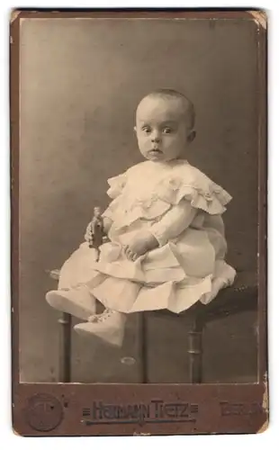 Fotografie Hermann Tietz, Berlin, Leipziger-Strasse, Baby mit weissem Kleidchen auf Stuhl