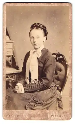 Fotografie F. Brandt, Flensburg, Portrait hübsches Mädchen im Biedermeierkleid mit geflochtenem hochgebundenem Zopf