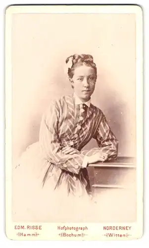 Fotografie Edm. Risse, Norderney, Portrait junge Frau im gestreiften Kleid mit hochgestecktem Zopf