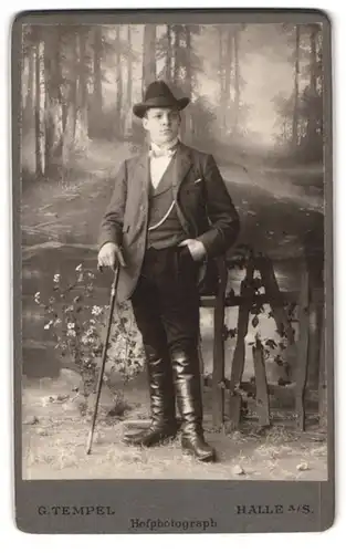 Fotografie G. Tempel, Halle a. S., Portrait junger Mann im Anzug mit Flanierstock und Lederstiefeln, Dandy