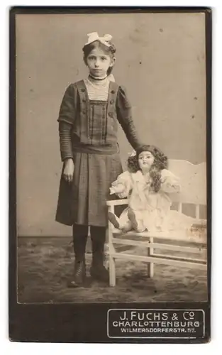 Fotografie J. Fuchs, Berlin, Wilmersdorferstr. 57, Portrait Mädchen im karierten Kleid mit grosser Puppe auf der Bank