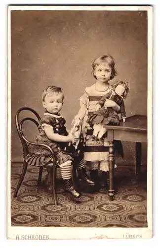 Fotografie H. Schröder, Lübeck, Beckergrube 150, Portrait zwei kleine Kinder mit ihrer Puppe im Atelier