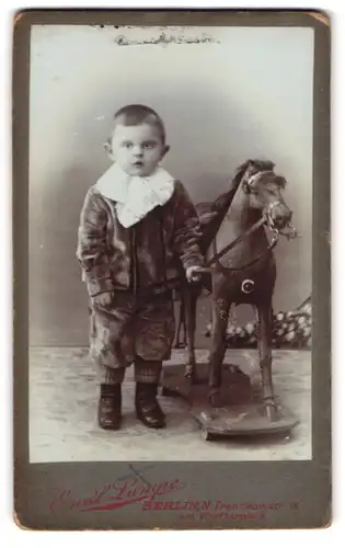Fotografie Emil Lampe, Berlin, Tresckowstr. 18, Portrait junger Knabe im Samtanzug mit seinem Schaukelpferd