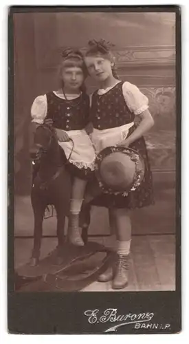 Fotografie E. Burons, Bahn i. P., Portrait zwei zwillings Mädchen in Kleidern auf einem Schaukelpferd