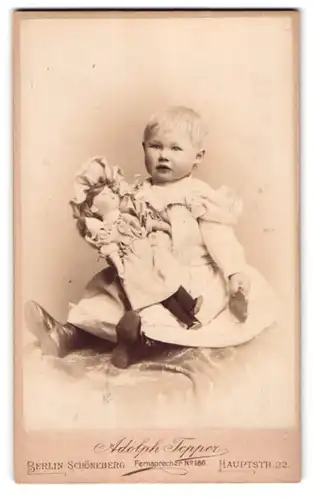 Fotografie Adolph Tepper, Berlin, Hauptstr. 22, Portrait kleines Mädchen im Kleid mit grosser Puppe im Arm