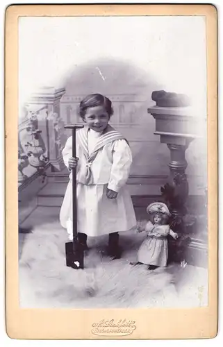 Fotografie A. Lickfett, Bischofswerder, Portrait kleines Mädchen im weissen kleid mit Puppe auf Eisbärfell