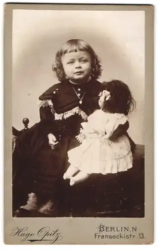 Fotografie Hugo Opitz, Berlin, Franseckistr. 13, Portrait blondes Mädchen im dunklen Kleid mit grosser Puppe im Arm