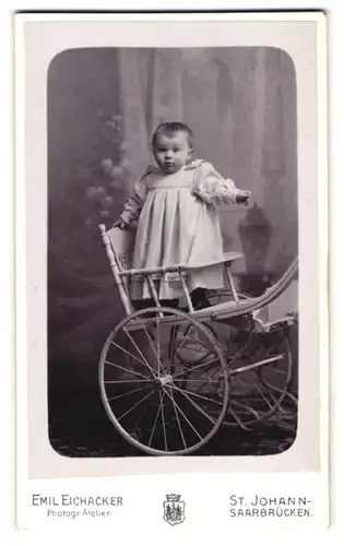 Fotografie Emil Eichacker, St. Johann, Portrait niedliches Kleinkind stehend im Kinderwagen