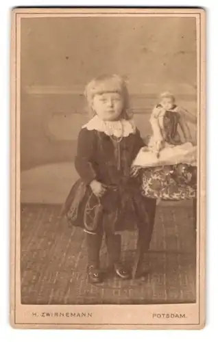 Fotografie H. Zwirnemann, Potsdam, Portrait kleines blondes Mädchen im Samtkleid mit ihrer Puppe