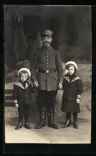 AK Soldat steht mit zwei Kindern an den Händen im Fotostudio, Uniformfoto