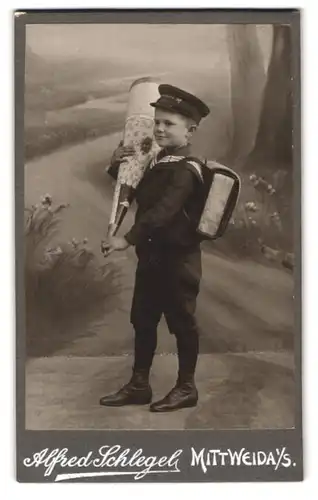 Fotografie Alfred Schlegel, Mittweida i. S., Portrait niedliche Knabe in Schuluniform mit grosser Zuckertüte und Ranzen