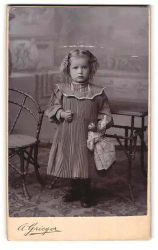 Fotografie A. Grieger, Berlin, Friedensstr. 8, Portrait niedliches Mädchen im gerafften Kleidchen mit Puppe in der Hand
