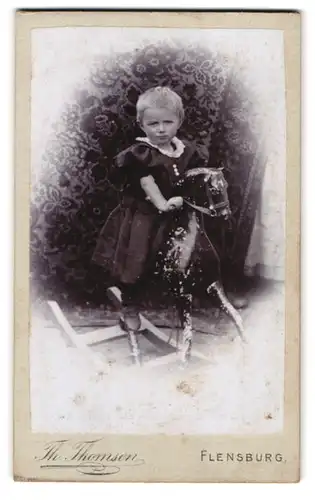 Fotografie Th. Thomsen, Flensburg, Portrait kleines Mädchen im Kleidchen auf ihrem Schaukelpferd