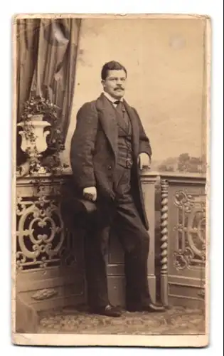 Fotografie Th. Schuhmann & Sohn, Carlsruhe, Portrait Herr im Anzug mit Zylinder und Moustache posiert im Atelier