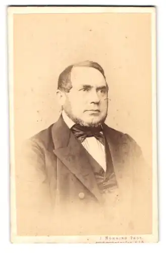 Fotografie J. Nöhring, Lübeck, Portrait korpulenter Herr im Anzug mit Fliege und Kinnbart