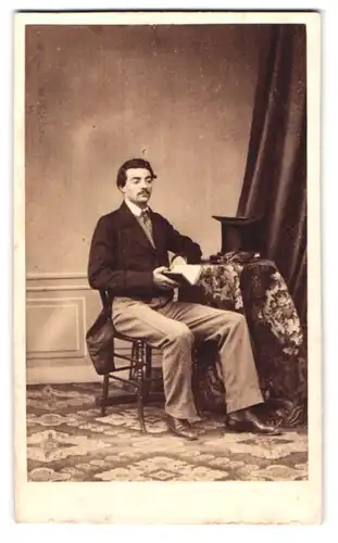 Fotografie A. Briquet, Paris, Boul. des Italiens 11, Portrait junger Mann im Frack mit Zylinder sitzend am Tisch