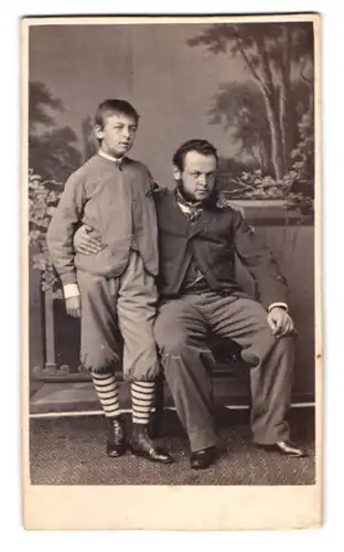 Fotografie unbekannter Fotograf und Ort, Portrait Vater im Anzug mit seinem Sohn im Atelier