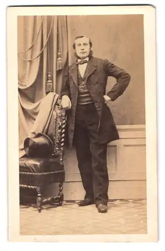 Fotografie unbekannter Fotograf und Ort, Portrait Herr im Anzug mit Backenbart udn Zylinder auf dem Stuhl